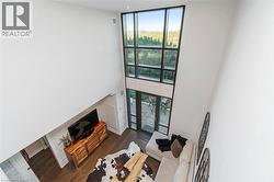 Double-height great room featuring expansive, multi-pane windows and glass doors leading to an outdoor patio - 