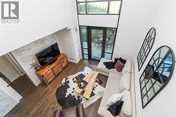Double-height living area featuring wood-finish flooring and a white stacked stone wall - 