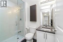 Bathroom featuring a glass-enclosed shower, white vanity with a dark countertop, integrated sink, and contemporary fixtures - 
