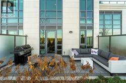 Private patio featuring paver flooring, frosted glass privacy screens, and a wall-mounted exterior light fixture - 