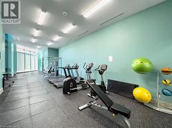Dedicated fitness center featuring rubber flooring, abundant natural light from large windows, and overhead fluorescent lighting - 
