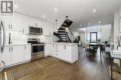 Modern kitchen featuring white cabinetry, stainless steel appliances, hexagon tile backsplash, and light-toned countertops - 