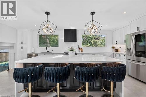 Spacious kitchen island with a light-toned countertop, complemented by a stainless steel refrigerator and dishwasher - 9 Leslie Drive, Hamilton, ON - Indoor