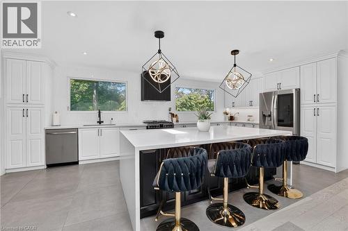 Contemporary kitchen featuring white shaker cabinetry, stainless steel appliances, and a large central island with a white countertop - 9 Leslie Drive, Hamilton, ON - Indoor