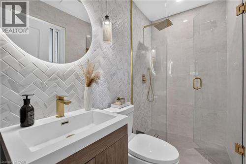 Contemporary bathroom featuring a floating wood-finish vanity with an integrated rectangular sink and gold-tone faucet - 9 Leslie Drive, Hamilton, ON - Indoor Photo Showing Bathroom