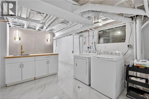 Laundry area featuring white appliances, a wood-finish countertop, a built-in sink with a gold-finish faucet, and a stone-look backsplash - 9 Leslie Drive, Hamilton, ON - Indoor Photo Showing Laundry Room