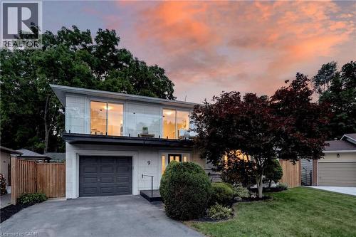 Modern two-story residence featuring a ground-level garage, upper-level balcony with glass railing, and a paved driveway - 9 Leslie Drive, Hamilton, ON - Outdoor