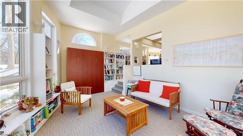 Living area featuring vaulted ceilings, built-in shelving, large windows with exterior views, a built-in wall unit, and a pass-through opening to an additional space - 919 Montgomery Drive, Ancaster, ON 