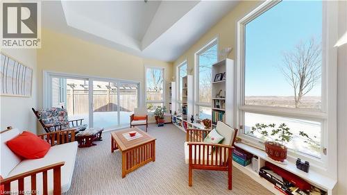 Sunroom featuring a vaulted ceiling with skylight, expansive windows, built-in shelving, and direct outdoor access via sliding glass doors - 919 Montgomery Drive, Ancaster, ON 