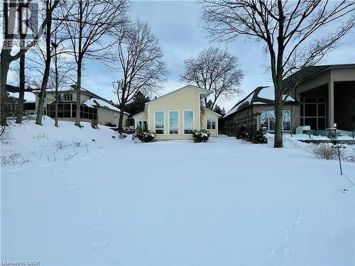 Yellow exterior featuring multiple large windows, a light-colored roof, and perimeter shrubbery - 919 Montgomery Drive, Ancaster, ON 