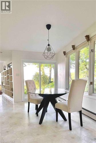 Bright interior space featuring a geometric pendant light fixture, extensive window line, and patterned flooring - 919 Montgomery Drive, Ancaster, ON 