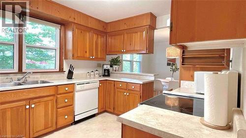 Kitchen featuring wood cabinetry, light-toned countertops, a stainless steel double-basin sink, and a white dishwasher - 919 Montgomery Drive, Ancaster, ON 