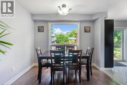 Dining area featuring wood-finish flooring and a single window overlooking a fenced yard - 