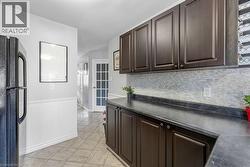Kitchen featuring dark wood-finish cabinetry, solid surface countertops, and a textured tile backsplash - 