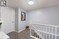 Upper landing featuring wood-finish flooring and a white paneled door - 