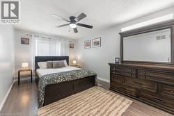 Bedroom featuring wood-finish flooring, a ceiling fan, and a window with blinds - 