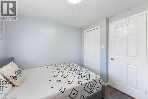 Interior room featuring light gray walls, wood-finish flooring, a white paneled door with a chrome knob, and a white bi-fold closet door - 33 Remple Court, Cambridge, ON 