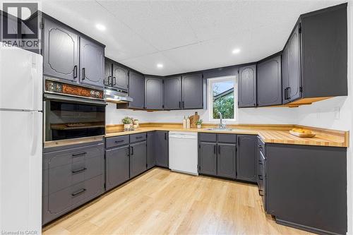 Kitchen featuring dark cabinetry, light wood-finish countertops, stainless steel sink, and light wood-finish flooring - 11 Ford Street, Hamilton, ON 