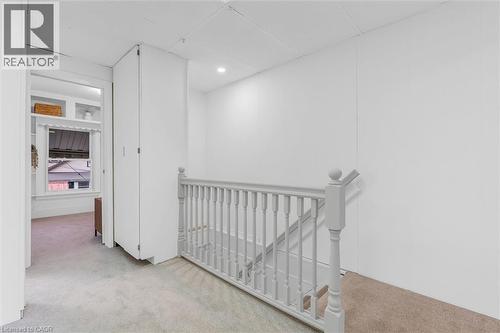 Upper level landing featuring light-toned carpeting, white painted paneling, and a painted wood balustrade - 11 Ford Street, Hamilton, ON 