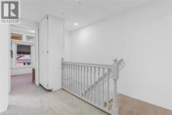 Upper level landing featuring light-toned carpeting, white painted paneling, and a painted wood balustrade - 