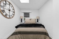 Compact bedroom featuring a window, built-in shelving, and recessed ceiling lighting - 