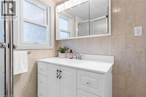 Bathroom featuring a white vanity with integrated sink, chrome faucet, and a wall-mounted mirrored medicine cabinet - 11 Ford Street, Hamilton, ON 