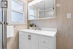Bathroom featuring a white vanity with integrated sink, chrome faucet, and a wall-mounted mirrored medicine cabinet - 
