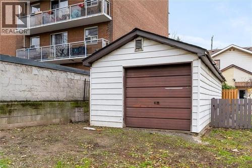 Detached single-car garage featuring a brown sectional door and white horizontal siding - 11 Ford Street, Hamilton, ON 