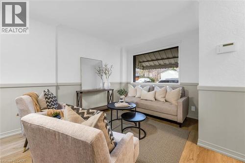 Living area featuring light wood-finish flooring, two-tone wall treatment with wainscoting, and a large window providing natural light - 11 Ford Street, Hamilton, ON 