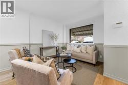 Living area featuring light wood-finish flooring, two-tone wall treatment with wainscoting, and a large window providing natural light - 