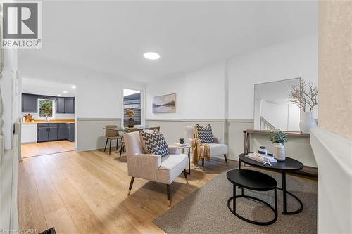 Spacious living area featuring light wood-finish flooring, a neutral color palette with a two-tone wall design, and a circular recessed light fixture - 11 Ford Street, Hamilton, ON 