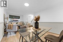 Open-concept living area featuring light wood-finish flooring, white walls with wainscoting, and recessed lighting - 
