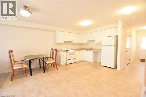 Open-concept kitchen and dining area featuring light-toned flooring, white cabinetry, integrated appliances, and a neutral wall palette - 52 Meadowridge Street, Kitchener, ON 