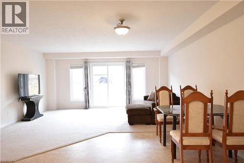 Bright main living area featuring a sliding glass door for outdoor access, a large window, and light-toned walls - 52 Meadowridge Street, Kitchener, ON 