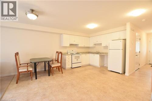 Open-concept kitchen featuring white cabinetry, light-toned countertops, and a white appliance suite including a refrigerator and range - 52 Meadowridge Street, Kitchener, ON 