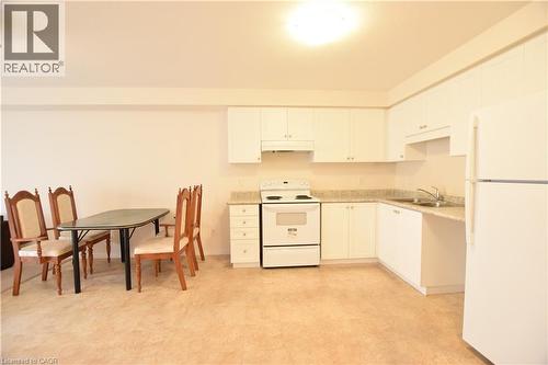 Open-concept kitchen featuring white cabinetry, light-toned countertops, and a full suite of white appliances - 52 Meadowridge Street, Kitchener, ON 