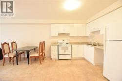Open-concept kitchen featuring white cabinetry, light-toned countertops, and a full suite of white appliances - 