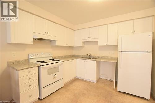 Kitchen featuring white cabinetry, light-toned countertops, a white electric range, and a white refrigerator - 52 Meadowridge Street, Kitchener, ON 