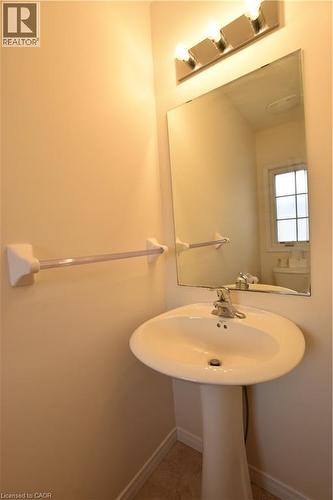 Pedestal sink with chrome faucet, large wall-mounted mirror, and vanity lighting - 52 Meadowridge Street, Kitchener, ON 
