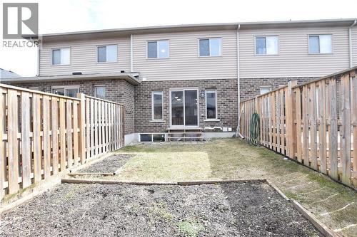 Fenced backyard featuring a small lawn area and garden beds - 52 Meadowridge Street, Kitchener, ON 