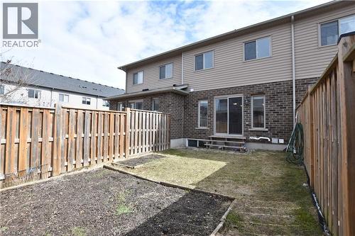 Rear exterior featuring brick and siding construction, a sliding glass patio door, and a private wooden fence - 52 Meadowridge Street, Kitchener, ON 