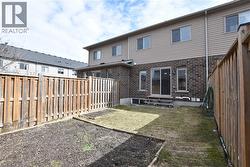 Rear exterior featuring brick and siding construction, a sliding glass patio door, and a private wooden fence - 