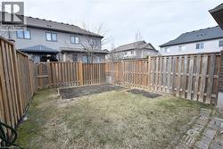 Private backyard with wood fencing, featuring a grass lawn, two raised garden beds, and a brick paver pathway - 