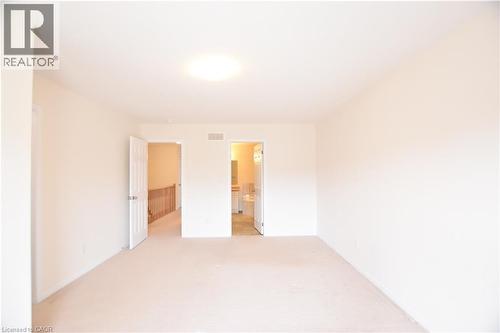 Carpeted interior space featuring neutral wall tones, a flush-mount ceiling light, and white trim - 52 Meadowridge Street, Kitchener, ON 