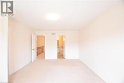 Carpeted interior space featuring neutral wall tones, a flush-mount ceiling light, and white trim - 