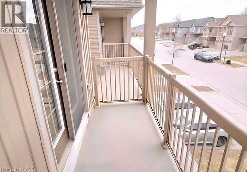 Private balcony featuring a light-toned railing system, exterior wall lantern, and sliding glass door with a screen - 52 Meadowridge Street, Kitchener, ON 