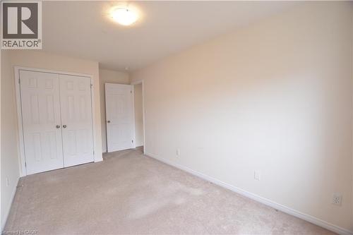 Recessed ceiling light fixture illuminating a spacious room with neutral-toned carpeting - 52 Meadowridge Street, Kitchener, ON 