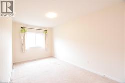 Bright room featuring a window with natural light, neutral wall paint, and plush carpeting - 