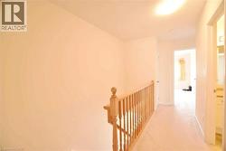 Upper level hallway featuring light-toned carpeting and neutral wall paint - 