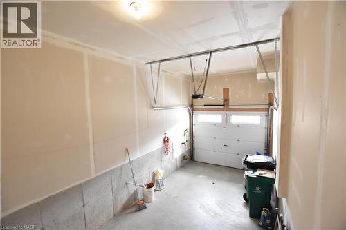 Attached garage with a sectional overhead door, automatic opener, and concrete flooring - 52 Meadowridge Street, Kitchener, ON 